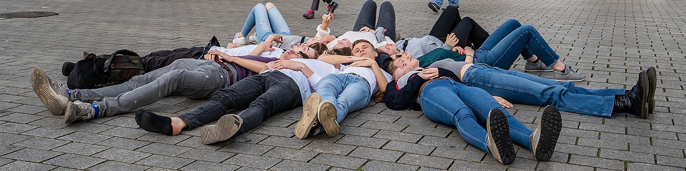 Klassenfahrt in Berlin - Schüler liegen sternförmig vor dem Brandenburger Tor.