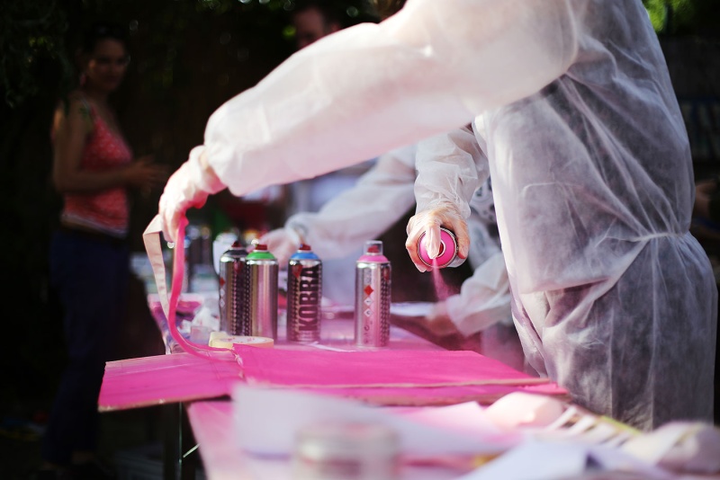 Mit einer pink-farbenden Sprühdose wird auf dem Graffiti-Workshop der Berlinpiloten auf Karton gesprüht.