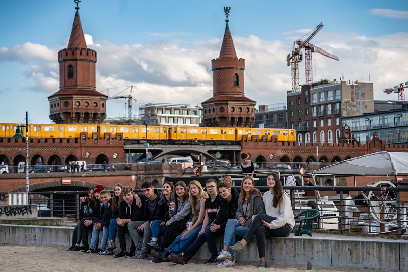 Schulklasse vor der Oberbaumbrücke in Berlin. Im Hintergrund fährt eine U-Bahn.