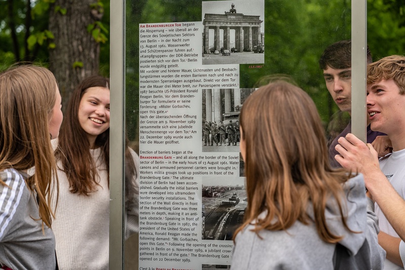 Schüler*innen lesen sich eine Infotafel im Berliner Tiergarten durch.