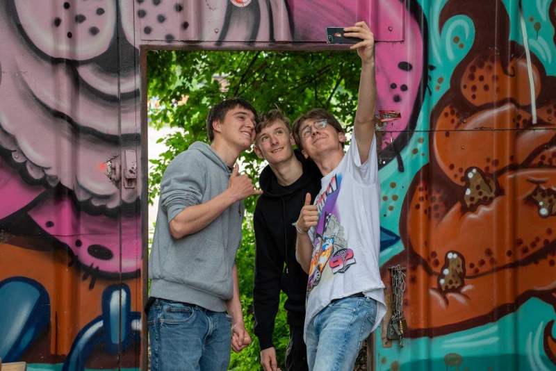 Schüler machen ein Selfie vor einer Streetart-Wand.